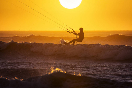 赤鸢冲浪者在埃萨乌拉摩洛哥日落时享受大浪。 背景的美丽景观