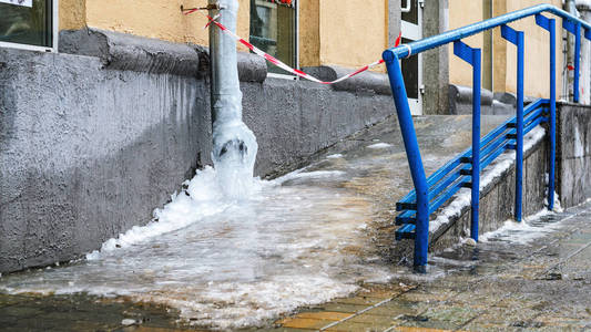 排水管里的冷冻水苦寒。 冬天冰柱从屋顶掉落的危险