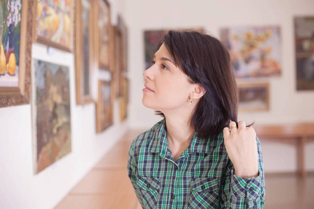 一个年轻漂亮的女人在美术馆看绘画。