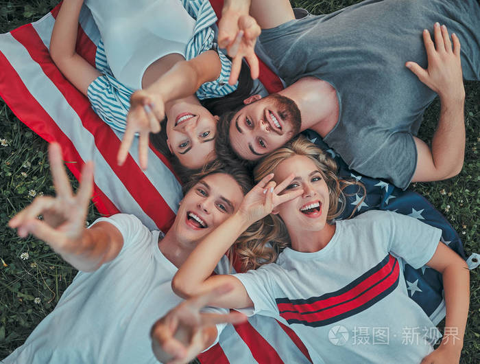 一群年轻人正在大学里一起学习. 户外的学生一起躺在美国国旗上.