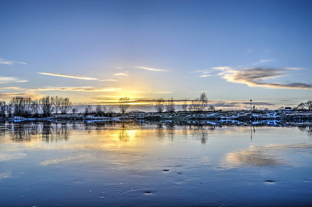 从荷兰Zutphen镇俯瞰，穿过缓慢流动的Ijssel河，在冬季日落时朝对岸走去。