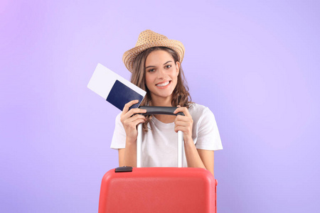 年轻的旅游女孩在夏天休闲服, 与太阳镜, 红色手提箱, 护照查出在紫色背景