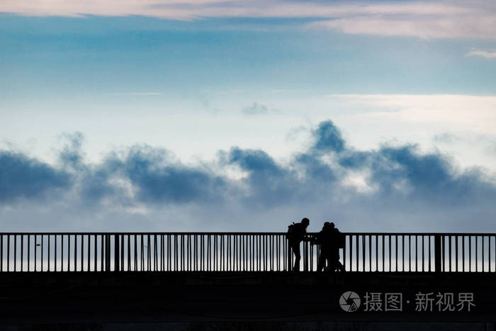 一群剪影的人站在河上的桥上黑白的