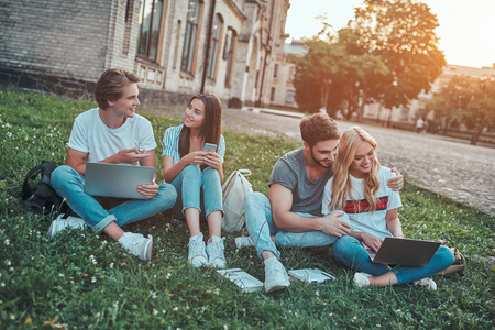 一群年轻人正在大学里一起学习。 学生们一起坐在草地上。