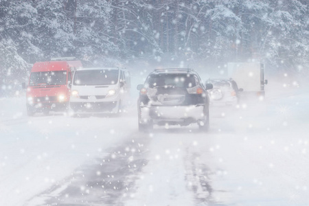 冬季暴风雪在道路上能见度差。 汽车在暴风雪中开着头灯