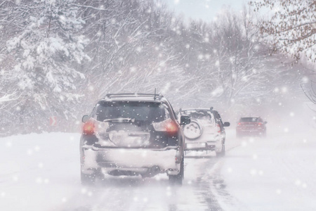 冬季暴风雪在道路上能见度差。 汽车在暴风雪中开着头灯