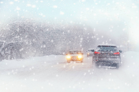 冬季暴风雪在道路上能见度差。 汽车在暴风雪中开着头灯