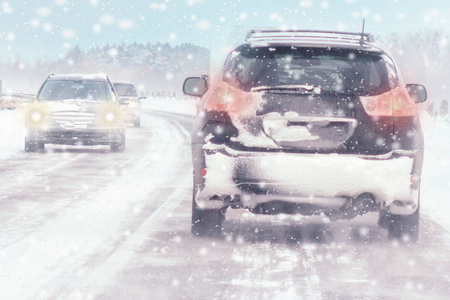 冬季暴风雪在道路上能见度差。 汽车在暴风雪中开着头灯