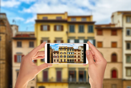 一位游客正在用手机拍摄意大利佛罗伦萨的德拉西诺里亚广场的意大利老建筑的美丽外观