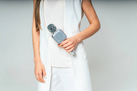 穿白色衣服的女人手里拿着灰色的麦克风. 快关门.照片