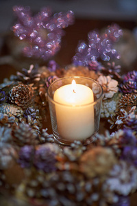 来临装饰花环蜡烛。 在黑暗中，一支蜡烛在一个美丽的装饰花环上燃烧。