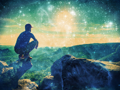 黑色长裤,外套和黑帽子的男人坐在悬崖边,看景观一个女孩舒适地坐在