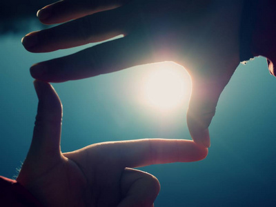 手握太阳女性手做手指形状的手势,手握太阳耀斑在海滩上.照片