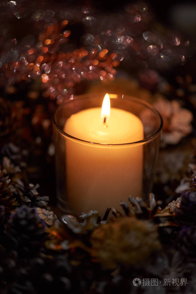 在黑暗中,一支蜡烛在一个美丽的装饰花环上燃烧.