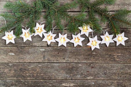 圣诞节主题舒适的温暖灯光，花环，星星和冷杉树枝在乡村的木制背景上。 上面的风景。 手一伸。 复制空间