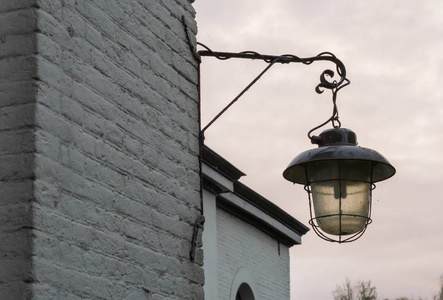 挂在砖墙上的未点亮的旧脏的老式街灯