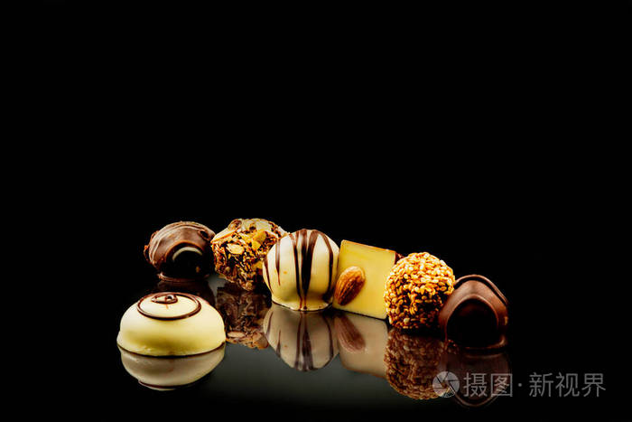 巧克力糖果在黑色镜面上洒满椰子片和榛子黑巧克力糖果甜蜜的时光