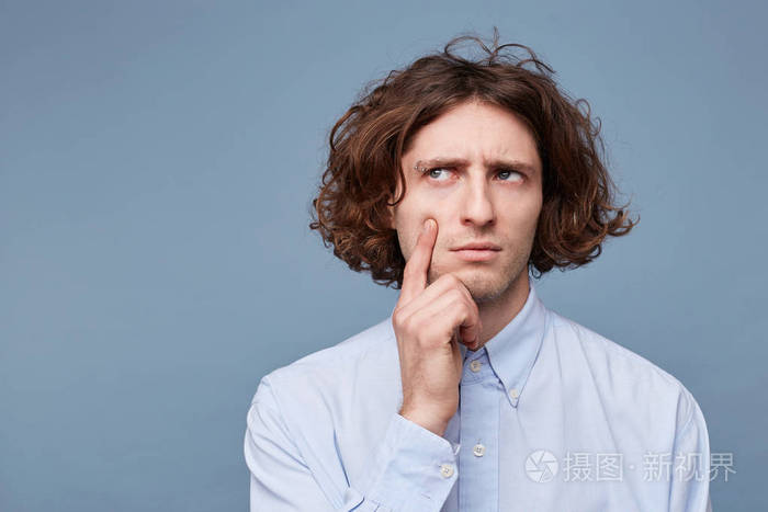 专注聪明有创造力的男性的肖像长发凌乱手指在脸颊和下巴上凝视着留下