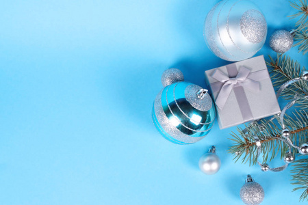 美丽的银礼品盒的组成与可爱的丝质弓和闪亮的圣诞珠和珠子附近的松树枝。 新年和圣诞节庆祝概念。 文本空间。