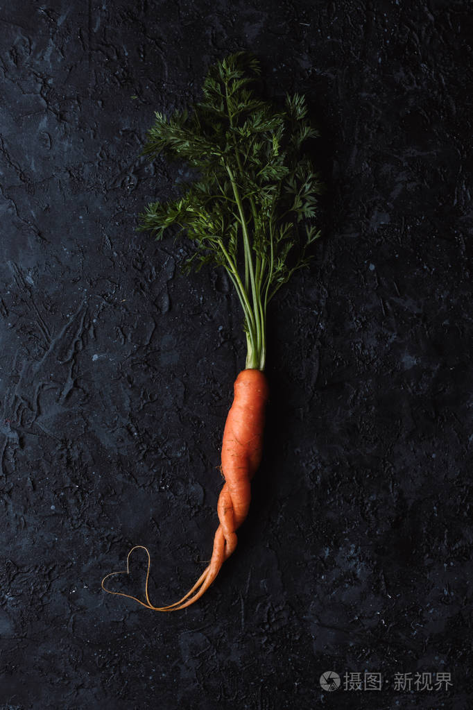 健康食品理念.新鲜的有机胡萝卜与心脏形状在黑色背景顶部的看法