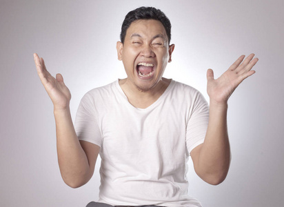 有趣的亚洲年轻人的肖像显示出胜利的姿态,张开嘴感到惊讶.