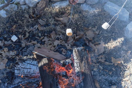 多个棉花糖延伸到一个营地的火烤。带棉花糖的壁炉，美味的白毛绒烤甜