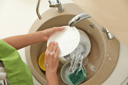 女人在厨房水槽里洗脏盘子。 打扫卫生