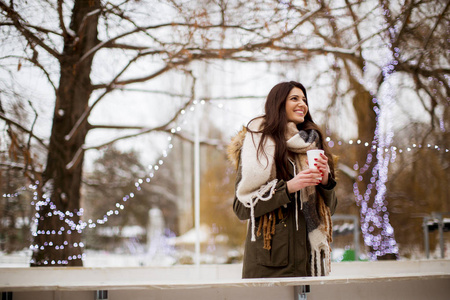 一位在雪地公园喝茶的年轻女子的肖像