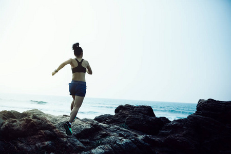 一个女人跑向海边的岩石山顶