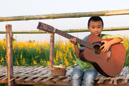男孩在美丽的阳光下弹吉他花园里的花朵