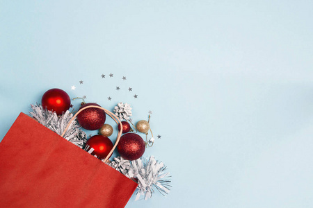 红色购物袋与圣诞节装饰在蓝色背景和复制空间。假日购物和折扣概念。