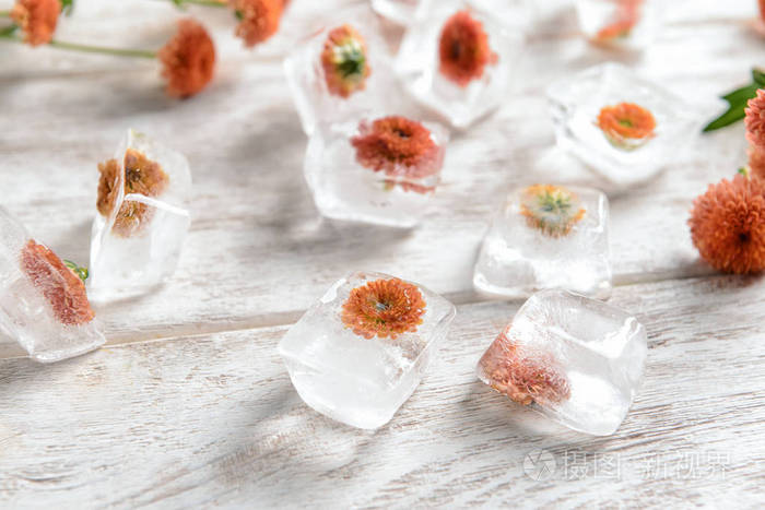 在浅木色的背景下冰冻在冰块上的美丽花朵