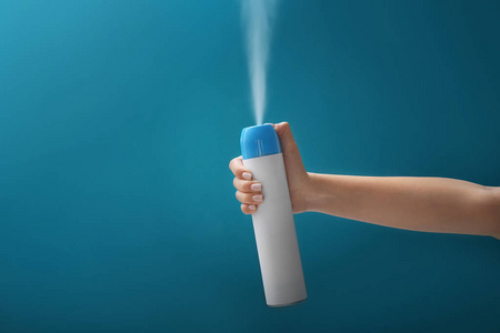 女性在彩色背景上喷洒空气清新剂照片