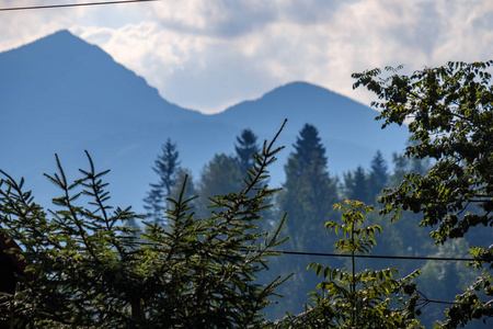 在晴朗的秋日，蓝色的天空和绿色的植被中，斯洛伐克塔特拉山上的薄雾中有遥远的山核