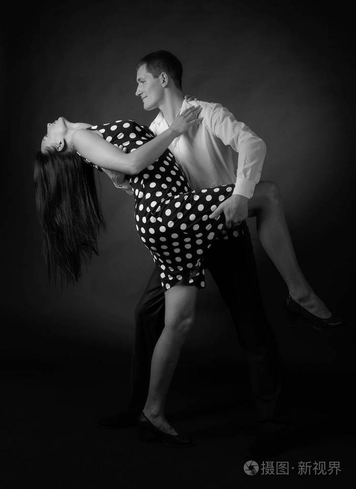 年轻漂亮的女人穿着圆点连衣裙,男人穿着白色衬衫跳探戈.
