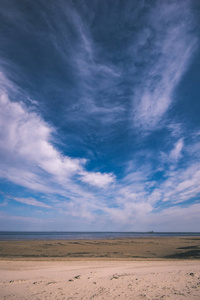 春天空海滩，地平线上有一些鸟和货船。 蓝天没有云彩复古复古