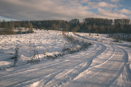 冬天的乡村冰雪覆盖的道路上有轮胎痕迹的外观