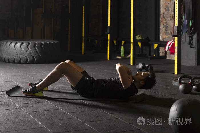年轻运动员在健身房练习仰卧起坐的黑色概念.