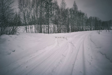 冬天的乡村冰雪覆盖的道路上有轮胎痕迹的外观