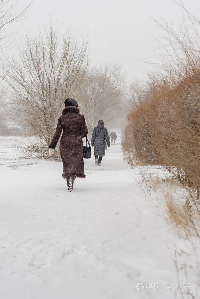 危险的冬天天气暴风雪大雪城市街道上滑溜溜的道路上行人在大雪下行走