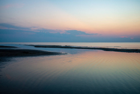 波罗的海清澈的海水上平静的蓝色日落。 具有直线地平线和波浪水中纹理的极简主义图像