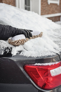 冬天恶劣的天气暴雪一个人用软毛刷把车窗从雪中擦干净