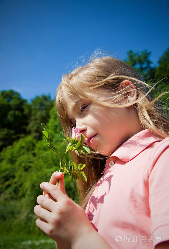 闻着粉红色花朵的年轻女孩