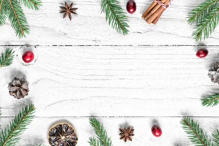 圣诞作文。 框架由冷杉枝，红色浆果，八角和松果在白色的木桌上覆盖着雪。 圣诞背景。 平躺着。 顶部视图，复制空间
