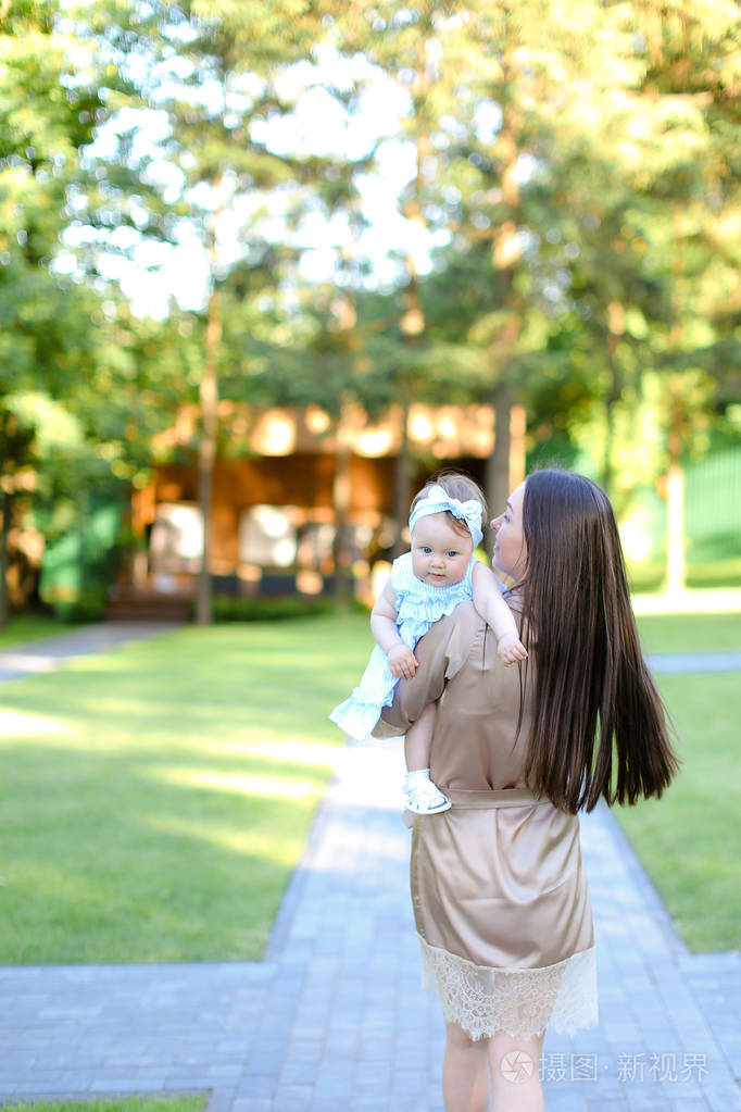 黑发女性在花园里抱着小婴儿的背景
