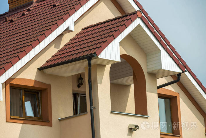 顶部的细节前面的大现代昂贵的住宅家庭别墅与剥落的棕色屋顶砖烟囱