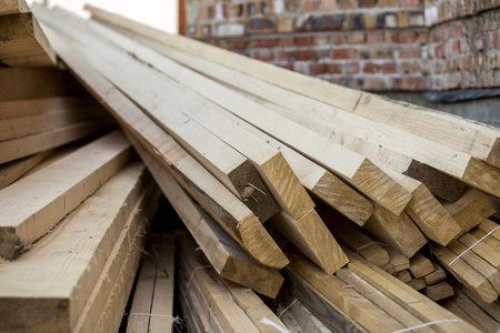 由明亮的阳光照亮的天然棕色凹凸不平的粗糙木板堆成的特写。木工建筑修理和家具用工业木材建筑用木材材料。