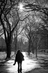 下雪时，女孩在大学校园里散步。