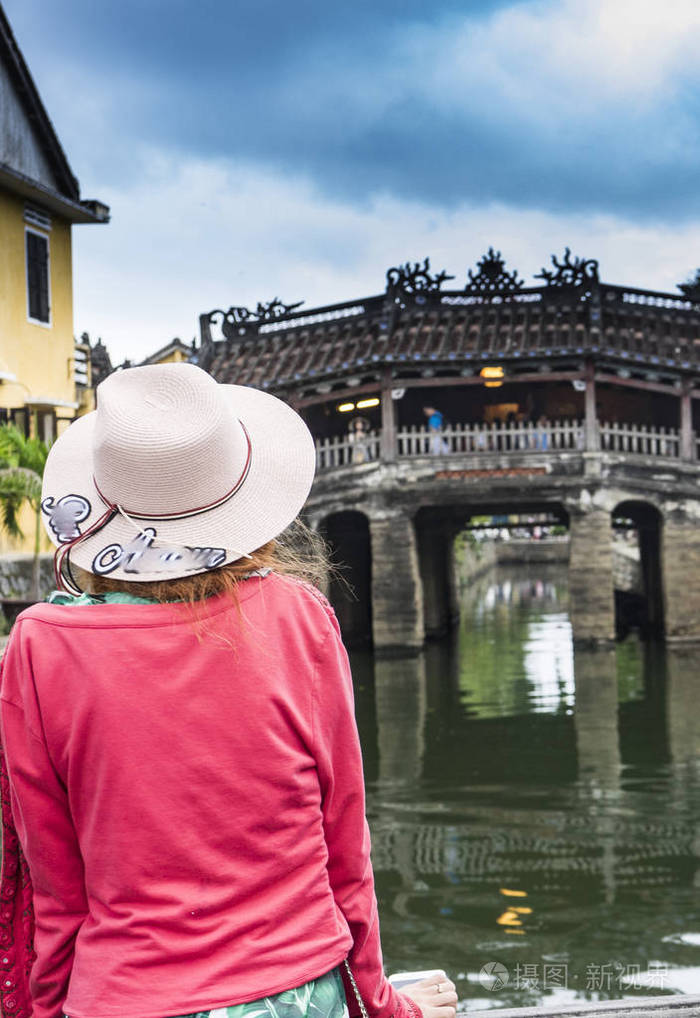 戴帽子的红发女孩游客正在海旅游,住在桥上,在古镇寻找古建筑和河流