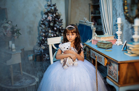 可爱的小女孩摆着圣诞装饰，穿着白色连衣裙和皇冠